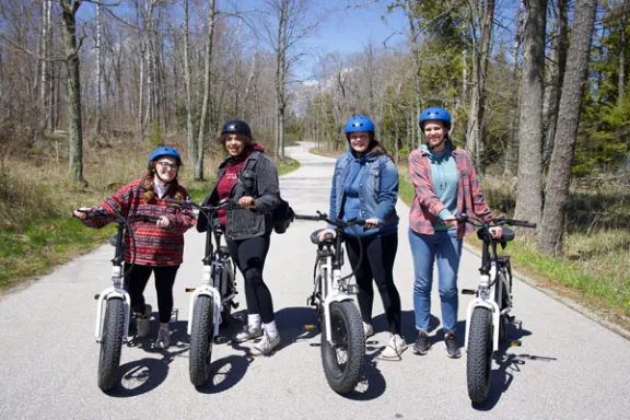 a group of people riding to cave point county park on electric bikes on a windy road in door county