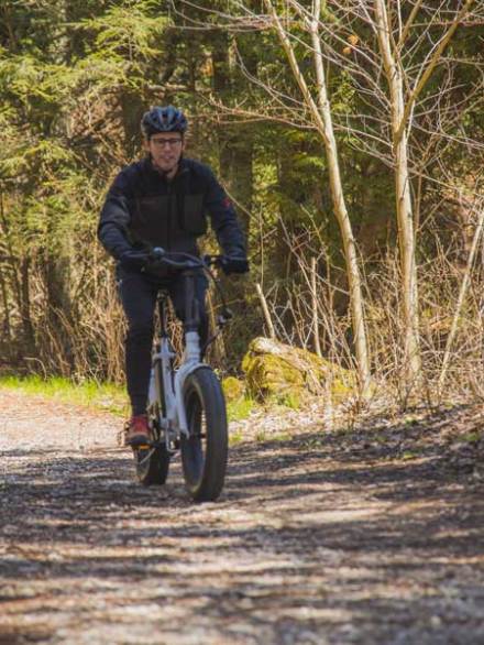 a man riding a fat tire ebike on a gravel path near whitefish bay dunes state park